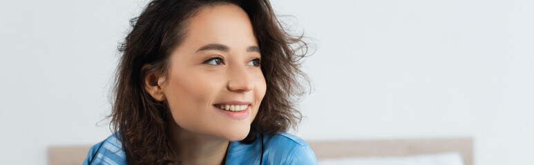 Fototapeta premium happy woman in blue pajamas looking away at home, banner.