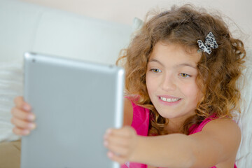 Child holding tablet in outstretched arms