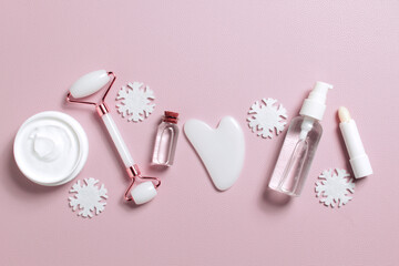Different skin care cosmetic products in unbranded containers on light pink background with Christmas decorations. Christmas cosmetic banner. Winter skin care products. Festive cosmetic sale concept.