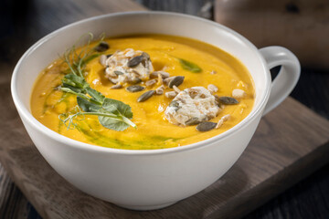 Pumpkin soup with pumpkin seeds on a wooden background