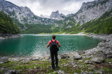 Man traveler enjoying view of Dachstein peak mountains on a Upper Gosau Lake. Gosau, Salzkammergut, Austria, Europe
