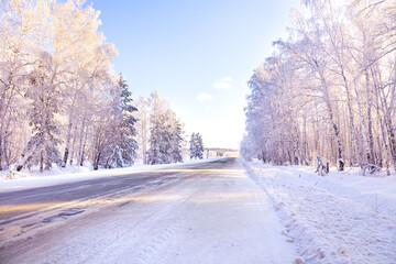 Fototapeta na wymiar Winter road and snow-covered trees at sunset. Winter landscape with birches in the snow.