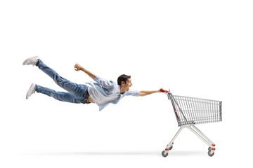 Full length shot of a casual guy man flying and holding an empty shopping cart