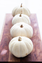 White mini pumpkins on wooden board