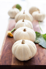 White mini pumpkins on wooden board