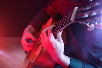The guy in the dark shirt is plucking the strings of a six-string guitar