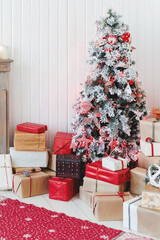 Christmas tree with presents. Fir tree decorated for New Year celebration with gifts packed in red and craft paper with decorations.