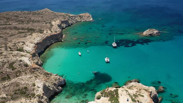 Aerial drone video of iconic volcanic white chalk sandy beach of Tsigrado with turquoise clear sea and rocky colour formations, Milos island, Cyclades, Greece