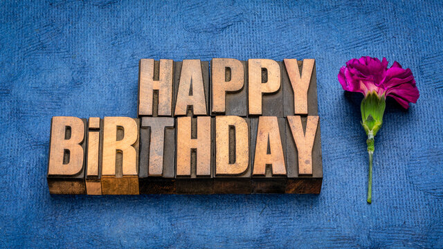 Happy Birthday greeting card in vintage letterpress wood type with a carnation flower against handmade bark paper