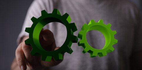 Mechanism, green metallic gears and cogs at work on brown background. Industrial machinery. 3D