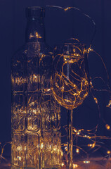 Vintage bottle, glass and shining Christmas lights	