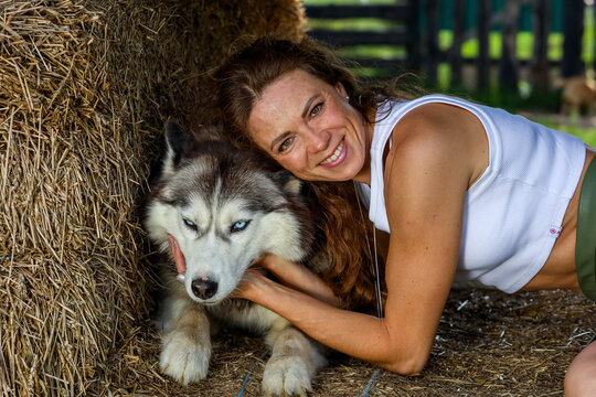 Beautiful red-haired woman hugging the husky. High quality photo
