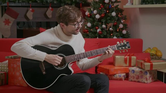 Smiling handsome man playing guitar singing 