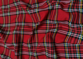 Red tartan woolen school uniform fabric material. Scottish classic seamless flannel cloth. Traditional wave pattern for a Christmas background or wallpaper. Black, Green, Red and White checkered.