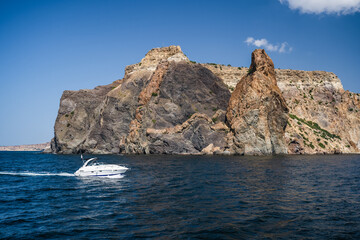 Pleasure tourist speed boat in black sea with volcanic rocks of Cape Fiolent in background, Sevastopol Crimea