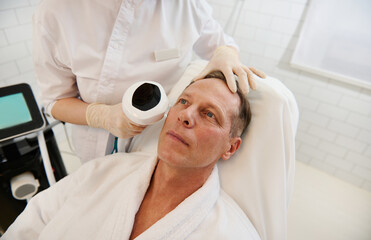 Handsome mature man receiving facial contouring procedure with meso threads for facial...