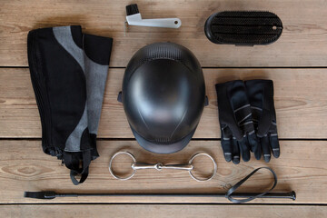 Black set of equipment for horse care and riding: helmet, whip, gloves, bridle, brushes on the...