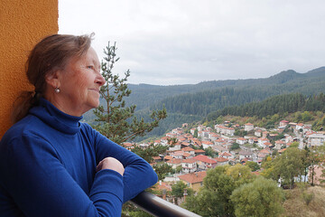 Fototapeta na wymiar portrait of a smiling elderly woman on a terrace with a gorgeous view of the mountains