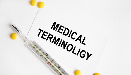 On the business card text MEDICAL TERMINOLIGY, next to the thermometer and yellow tablets.