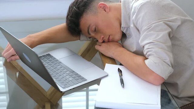 Close up business man put head on folded hands sleeping at workplace. Overloaded office employee tired of routine monotony paperwork. Unmotivated worker, insomnia and chronic fatigue syndrome concept
