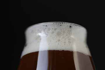 Beer foam with bubbles with reflection on glass on black background.