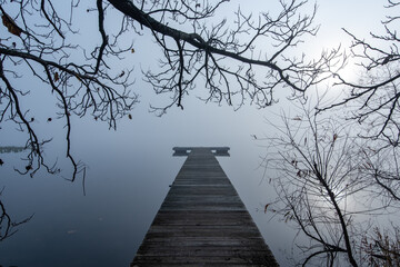 Misty foggy morning on lake with dock