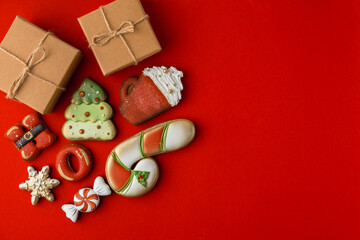 Flat lay of Christmas gingerbread cookies with festive icing and Christmas decoration on the red background. Merry Christmas and Happy New Year.