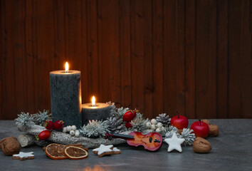 Weihnachtshintergrund: Kerzen mit Weihnachtsschmuck vor einem Holzhintergrund.