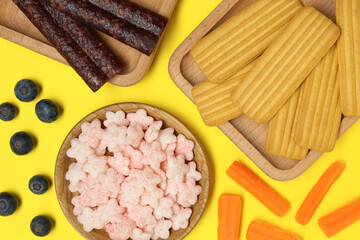 Different finger foods for baby on yellow background, flat lay