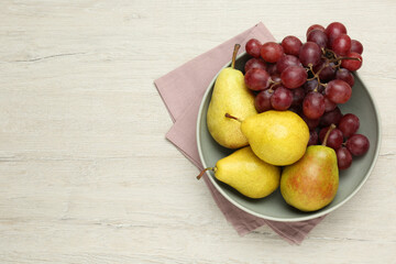 Fresh ripe pears and grapes on light wooden table, top view. Space for text
