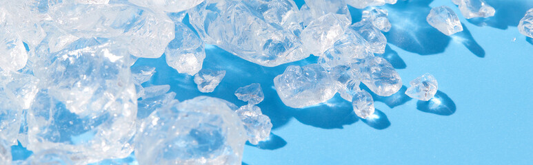 Close up crushed ice in sunlight on blue. Summer background refreshment concept