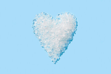 Fototapeta na wymiar Crushed ice in heart shape on blue background. Summer refreshment concept
