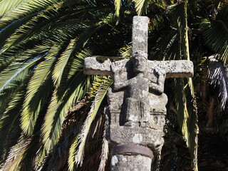 cruz de estilo románico y gótico con la escultura de jesús crucificado mirando al pueblo y en el...