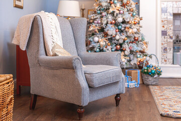 Classic Christmas decorated interior room, New year tree with silver decorations. Modern blue classical style interior design apartment with fireplace and armchair. Christmas eve at home.