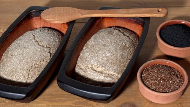Sourdough bread during rise time in clay rectangular moulds. Linseed and nigella seeds in bowls. Timelapse dough rise motion.
