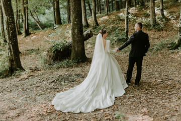 The bride and groom holding hands in the background of a forest