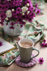 Cup of aromatic coffee, beautiful flowers and bright cloth on wooden table