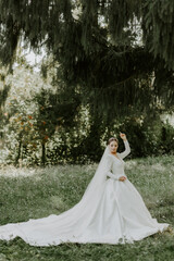 Beautiful bride in a white dress posing for the camera in a green garden