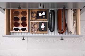 Open drawer with different stylish accessories indoors, top view. Storage and organizing