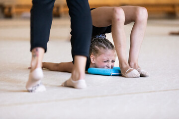 Girl gymnast doing difficult stretching exercise on training in gym