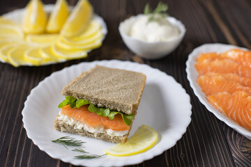 Sandwiches on two pieces of rye bread with cream, dill, cucumber and salmon in a white plate on a wooden boards background