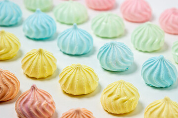 Multicolored meringues on a white background. Light and tasty dessert.