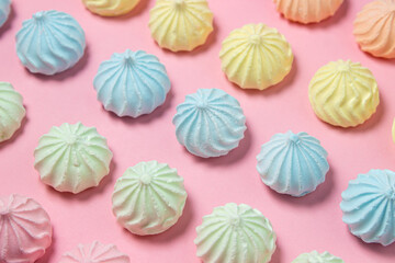 Multicolored meringues on a pink background. Meringue of different colors folded in several rows by color