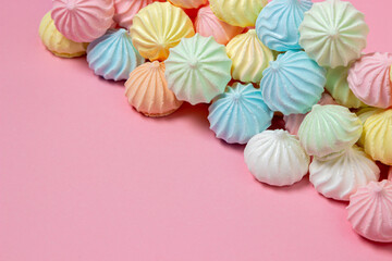 Multicolored meringues on a pink background. A pile of meringues on a bright background, there is a place for copy space