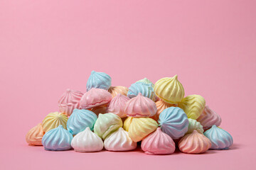 Multicolored meringues on a pink background. A pile of meringues on a bright background, there is a place for copy space