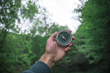 man holding compass in forest background