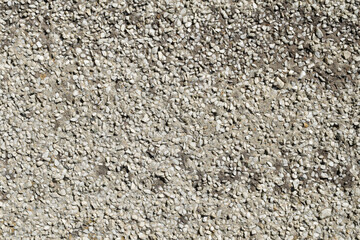 The texture of a gray cement wall interspersed with white marble chips.