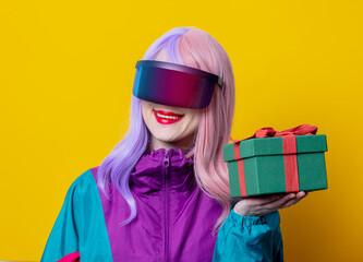 Style woman in VR glasses and 90s sport suit hold gift box on yellow background
