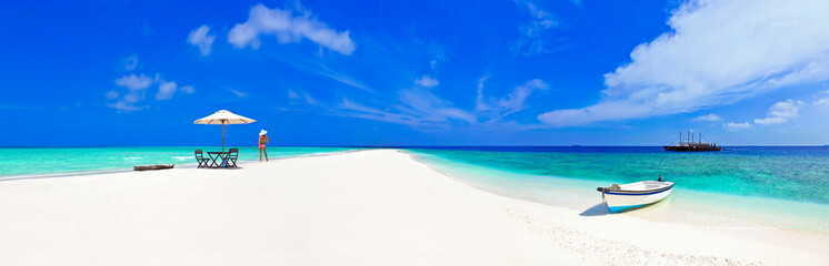 Beautiful Maldives beach with parasol and bikini model.