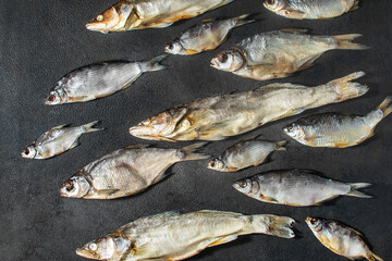 Fish, ready-made, dried, dry, salted, appetizing, many different varieties are laid out on a dark background. Catch, river, fishing. Guster, taranka, pike perch